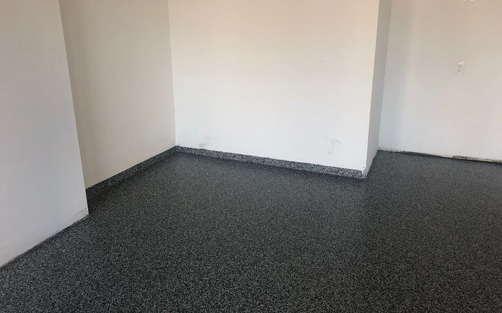 Flake floor coating carried up the base of the wall in an empty room