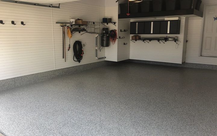 Garage with a gray flake floor, slatwall hooks and storage cabinets