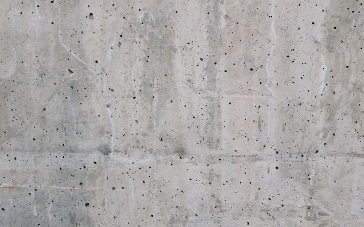 Gray concrete surface dotted with small pits and holes